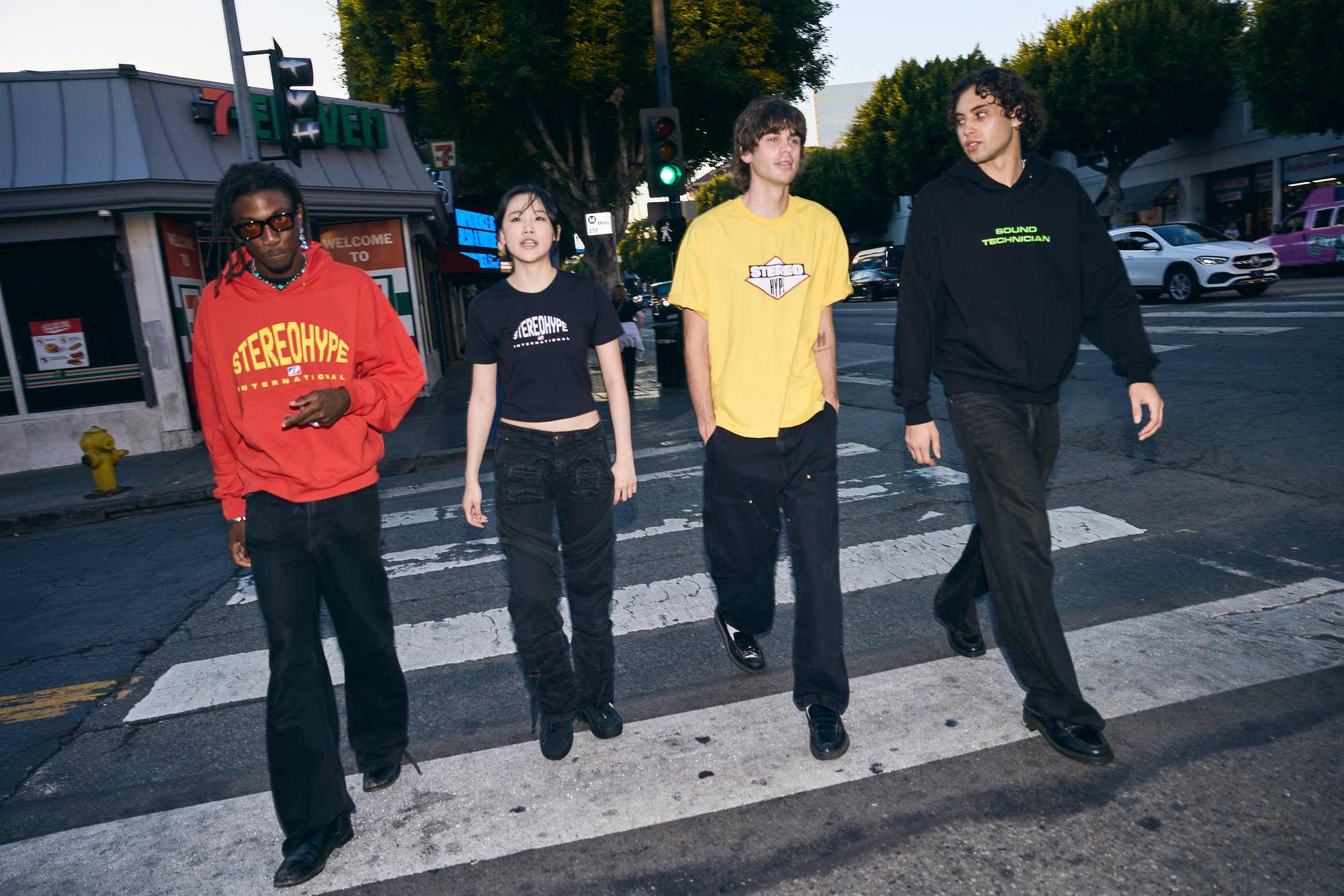 Four models crossing the street outside a 7-Eleven, wearing pieces from the new STEREOHYPE collection